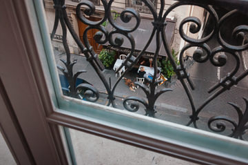 Cafe patrons on a quiet street in Paris, viewed from above.