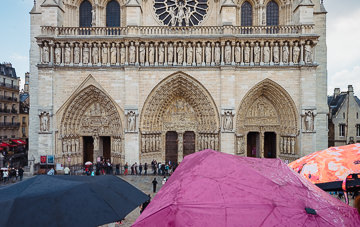 Umbrellas up at the west façade of Notre-Dame.
