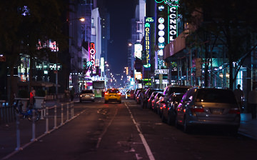 Taxi on dimly lit street outside the bright lights of Times Square.